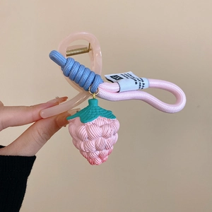 Close-up of cute strawberry hair claw clip with blue braided rope and pink resin detail