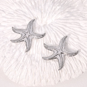 Boucles d'oreilles étoile de mer en acier inoxydable argenté sur fond corail blanc