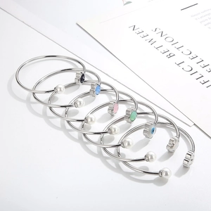 Detail showing five stackable silver open bangles with colorful floral charms and pearls