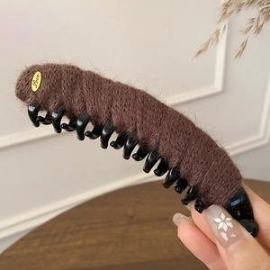 Close-up of brown plush hair claw clip with golden Love metal tag and soft texture