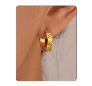 Close-up of 18k gold plated C-shaped earrings with inlaid zircon and screw motifs