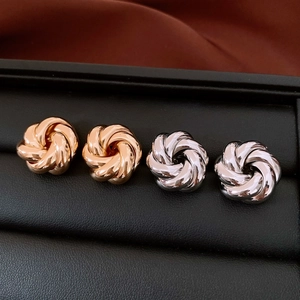 Close-up of elegant gold and silver knot stud earrings in a luxury display box