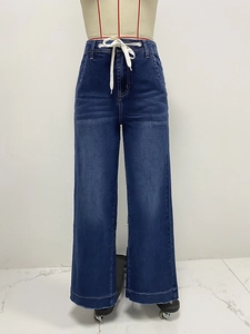 Detail view of deep blue wide leg jeans featuring high waist drawstring and vintage wash