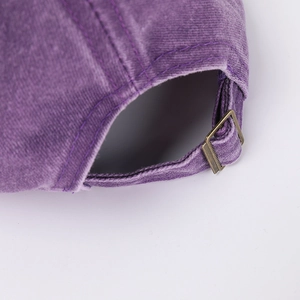 Close-up of washed purple cotton cap featuring an adjustable bronze metal buckle