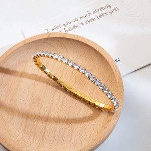 Vue détaillée du bracelet tennis doré serti de zircons sur un support en bois