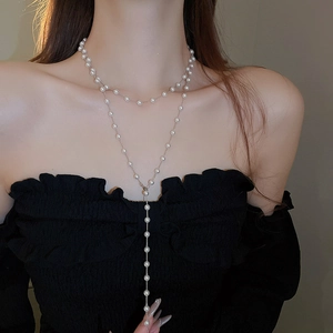 Détail d'un collier de perles artificielles superposé avec chaîne argentée sur modèle