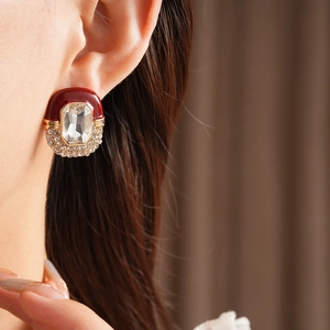 Detail of vintage oval earrings with red enamel and rhinestone accents on model ear