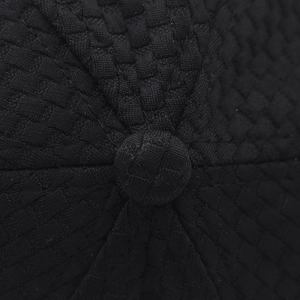 Macro shot of the top button and knitted grid texture on a black baseball cap
