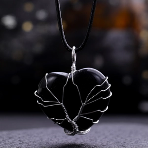 Macro detail of Tree of Life heart pendant with silver wire wrap on black obsidian stone