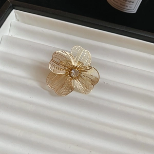 Close-up of golden hollow flower necklace pendant with rhinestone center on jewelry tray