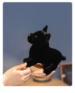 Close-up of a small black plush French Bulldog toy held in hand with soft textures