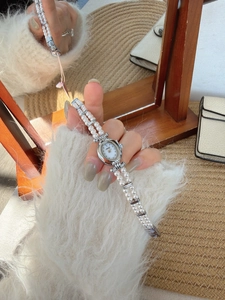 Detail of vintage oval shell watch with double-strand pearl bracelet on a woman wrist