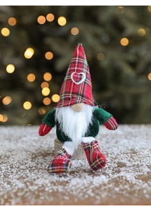 Detail of fabric Christmas gnome doll with red plaid hat and long white beard on snow