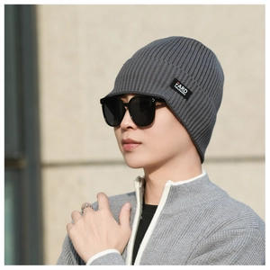 Detail view of a dark grey ribbed knit visor beanie with a branded side label on a model