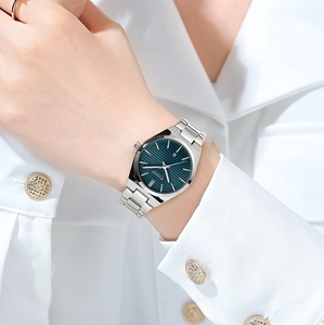 Detail of silver steel women's watch with teal dial and calendar window on wrist