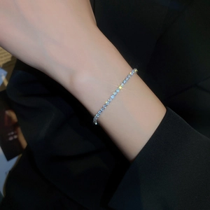 Détail d'un élégant bracelet tennis en argent et zircone porté au poignet sur fond noir