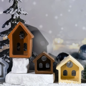 Trois moules en résine en forme de maison de tailles variées dans un décor d'hiver