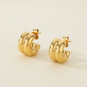 Close-up of polished gold-toned C-shaped hoop earrings with a smooth metallic finish