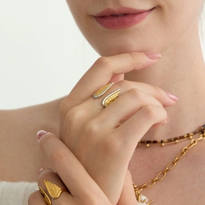 Detail of 18K gold and silver angel wing ring with stacked metal necklaces on model