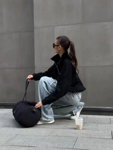 Detailed street style look with black zip-up sweatshirt and light blue ripped wide-leg jeans
