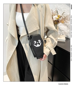 Black coffin-shaped crossbody bag with white pumpkin face print and silver side zipper