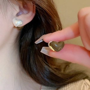 Gros plan de boucles d'oreilles cœur minimalistes en blanc perle et vert olive portées
