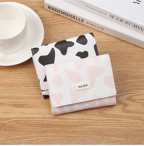 Close-up of foldable cow print mini wallets with milk heart label on a wooden desk