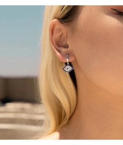 Detailed view of silver S925 evil eye huggie hoop earrings with blue gemstones on model