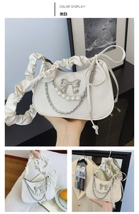 Detail view of off-white dumpling bag featuring pearl chains and metallic bow decorations