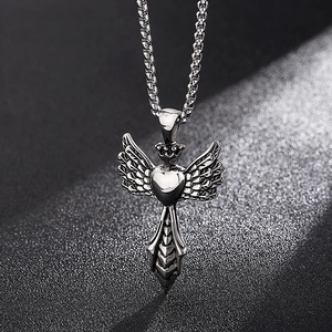 Macro view of stainless steel heart pendant with angel wings and crown on textured base