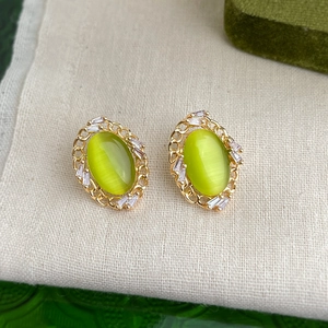 Macro view of gold flower earrings with olive green stone and zircon inlay