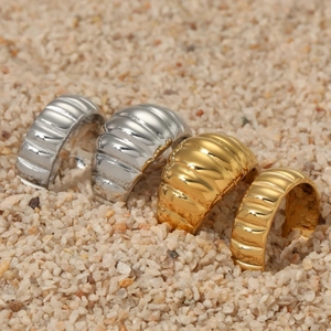 Polished gold and silver stainless steel croissant rings on textured stone background
