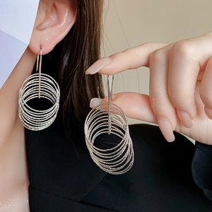 Close-up of silver multilayer hoop earrings with metallic finish on a model