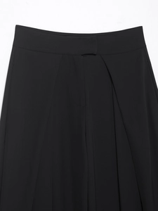 Detailed view of the pleated waistband and smooth fabric on black wide-leg trousers