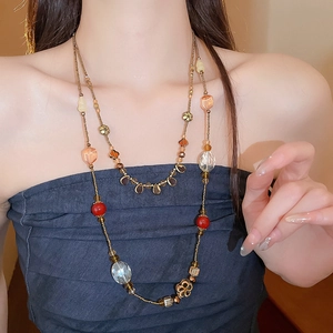Détail d'un collier vintage multicouche avec perles rouges et ambrées et fleurs dorées