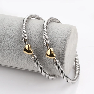 Detail of silver cable twisted cuff bracelet featuring gold heart motifs at the ends