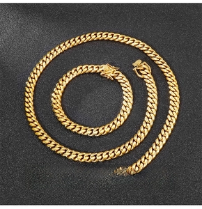 Detail of 8mm gold Cuban link chain set showing polished necklace and bracelet on black background