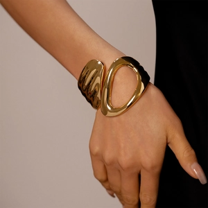 Detailed view of an asymmetric golden hollow geometric cuff bracelet on a model wrist