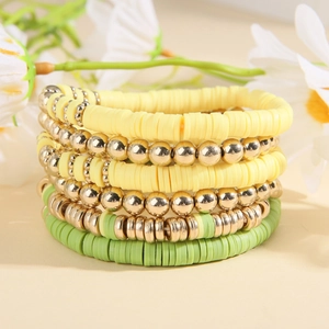Detail of bohemian multilayer heishi bead bracelets with yellow, green, and gold beads