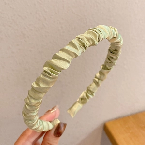 Close-up of light green pleated satin headband showing premium fabric texture