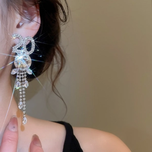 Gros plan sur de longues boucles d'oreilles à pompons avec strass et motif numéro 20