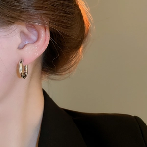 Close-up of elegant polished silver hoop earrings worn on a model with warm lighting