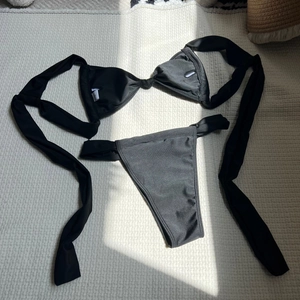 Detailed flat lay of black two-piece bikini set with halter top on waffle texture
