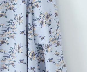 Detailed macro view of light blue fabric with bee and white flower prints on cuff