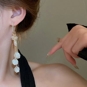 Gros plan de boucles d'oreilles à pompons avec pétales de nacre et strass sur mannequin
