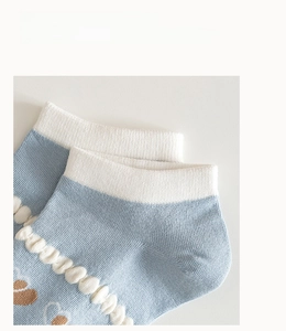 Dettaglio ravvicinato di calze in cotone azzurro con maglia fine e ricamo a cuore