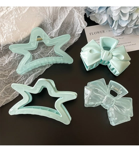 Flat lay of cream blue star and bow hair claws with floral decor on dark surface