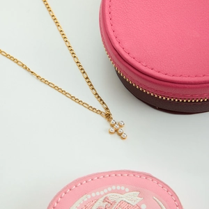 Close-up of golden cross pendant with white pearls on a Figaro chain with gift box