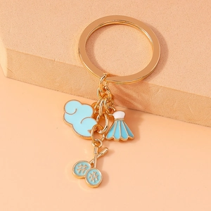 Close-up of golden badminton racket and blue cloud charms on a metal keychain