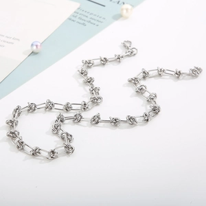 Close-up of a silver knot link chain necklace with a creative paperclip buckle design